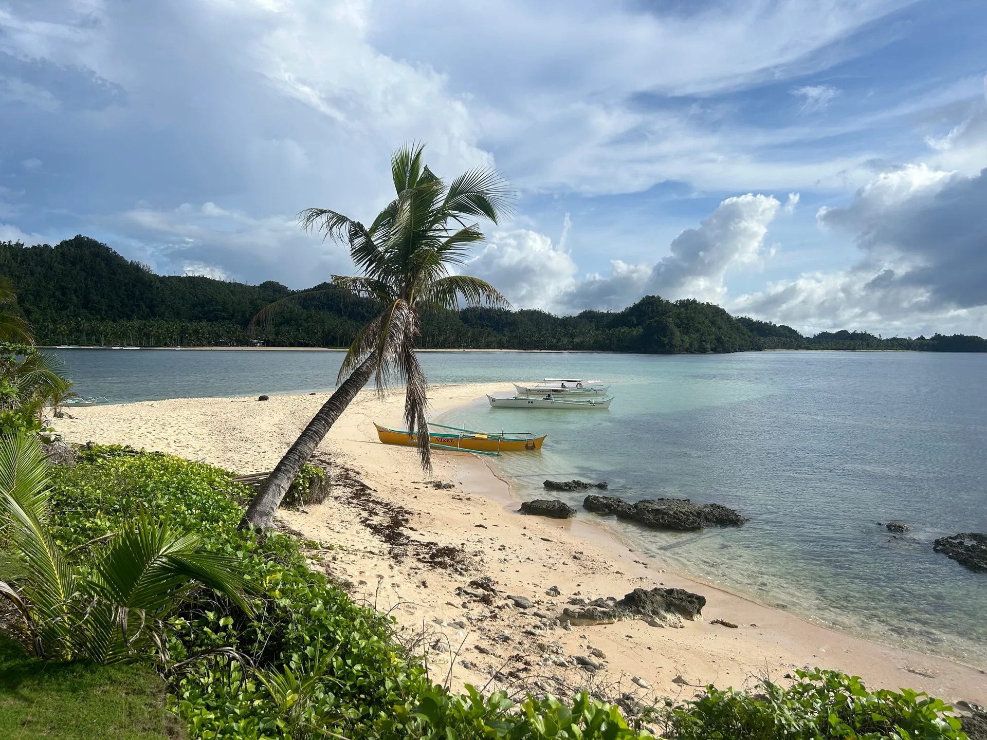 Outrigger boats moored along a white sand spit